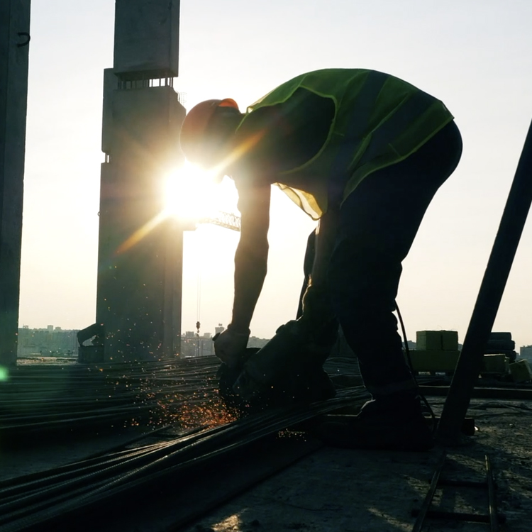 Man welding with sunshine behind