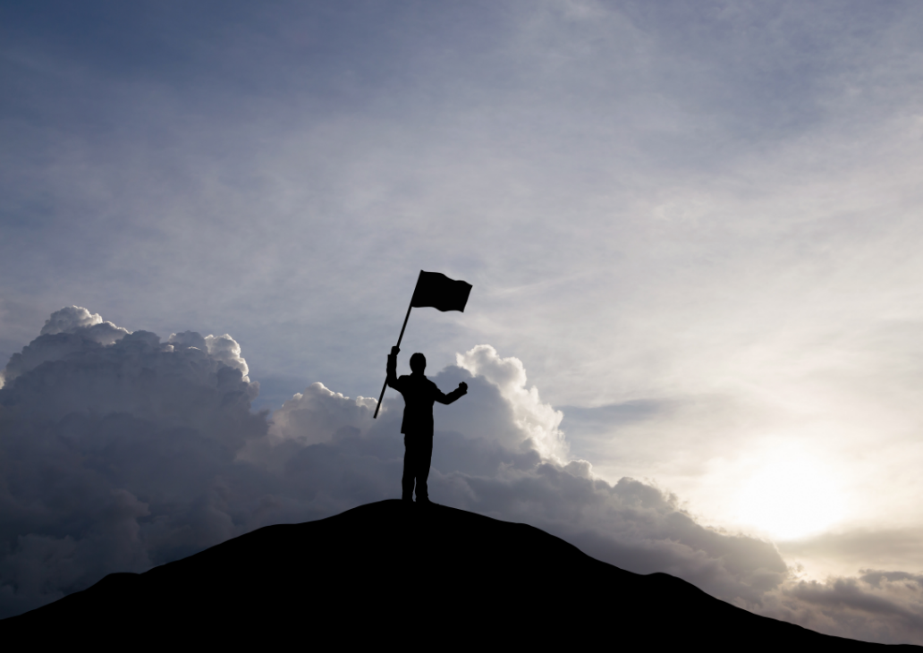 Man on top of cliff with flag